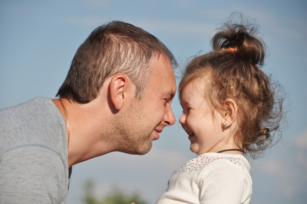 Happy father with his daughter outdoors hugging together - 写真・画像