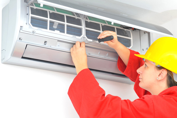 Trabajadora ajustando el sistema de aire acondicionado
 - Foto, Imagen
