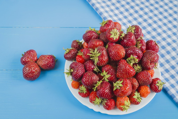 Fresh strawberry on the plate  blue background - Foto, afbeelding