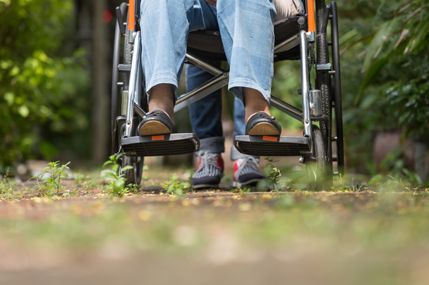 bejaarde vrouw in rolstoel wandelen met verzorger - Foto, afbeelding