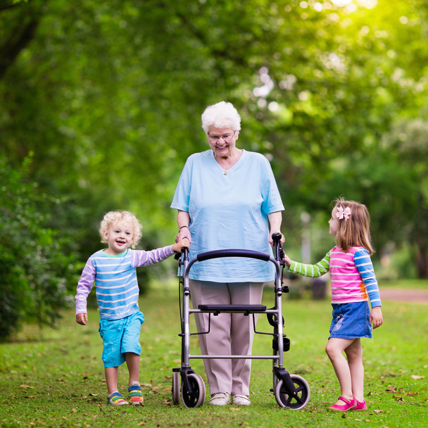 Grootmoeder met walker spelen met twee kinderen - Foto, afbeelding