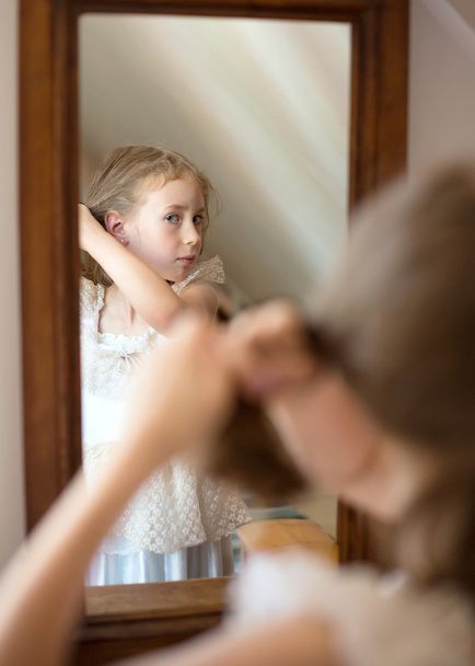 Little girl dresses up in front of the mirror. - 写真・画像