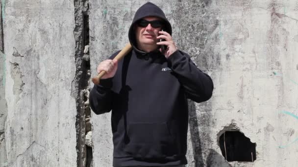 Homem com um bastão de beisebol falando no telefone inteligente
 - Filmagem, Vídeo
