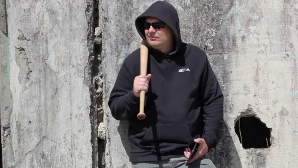 Hombre con un bate de béisbol mirando cerca de la pared
  - Imágenes, Vídeo