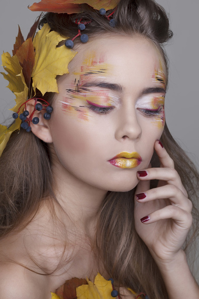 Beautiful girl with autumn make up and leaves on head - Фото, изображение