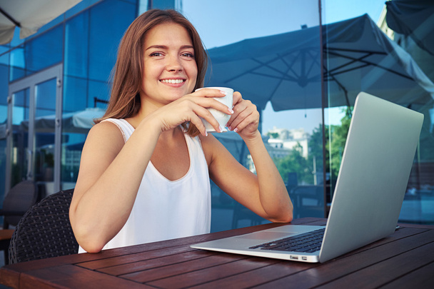 Portrait of smiling lady sitting on cafe open terrace with lapt - Foto, Imagem