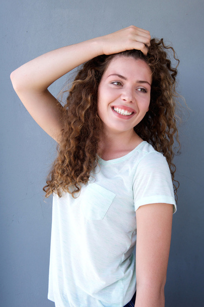 Usmívající se dívka stojící s rukou ve vlasech - Fotografie, Obrázek