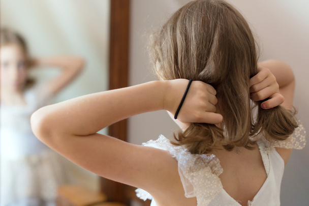Little girl dresses up in front of the mirror. - Valokuva, kuva