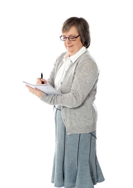 Senior woman writing in spiral notebook - 写真・画像