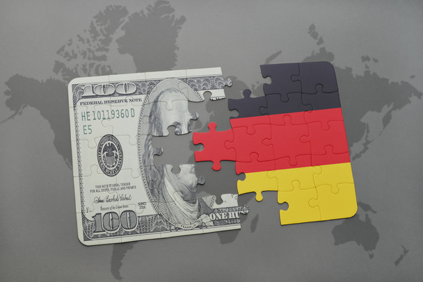 Puzzle mit der Nationalflagge Deutschlands und der Dollarnote auf einer Weltkarte. - Foto, Bild