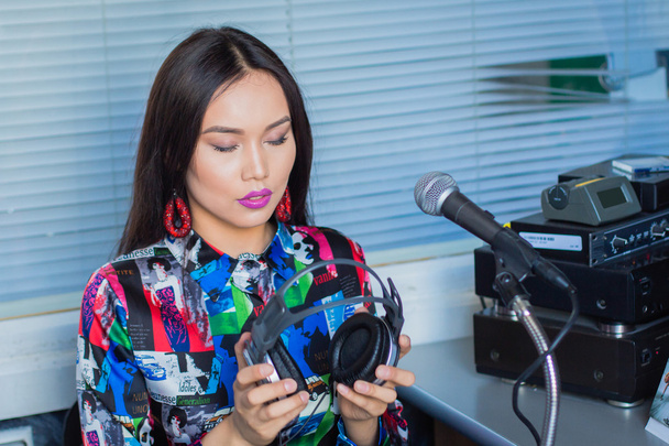 Chica en auriculares con un micrófono en la radio en el estudio
 - Foto, imagen