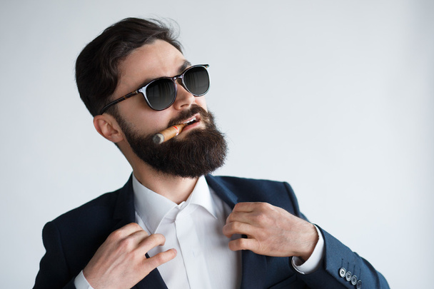 Attractive man with a cigar fixing his suit. - 写真・画像