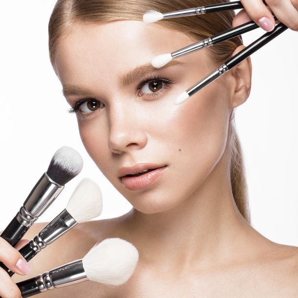Beautiful young girl with a light natural make-up, brushes for cosmetics and French manicure. Beauty face. - Foto, imagen