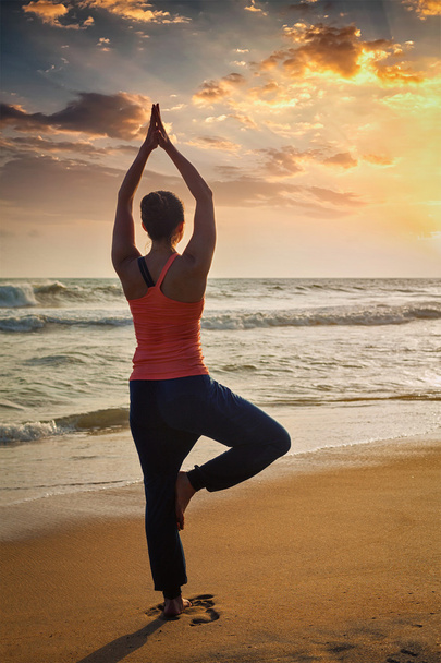Young sporty fit woman doing yoga tree asana on beach - Photo, Image