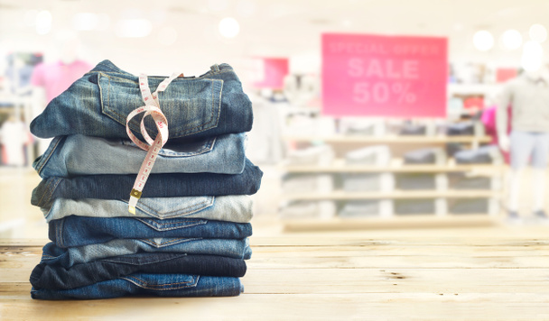 джинси з мірою в магазині на дерев'яній полиці та білому тлі
 - Фото, зображення