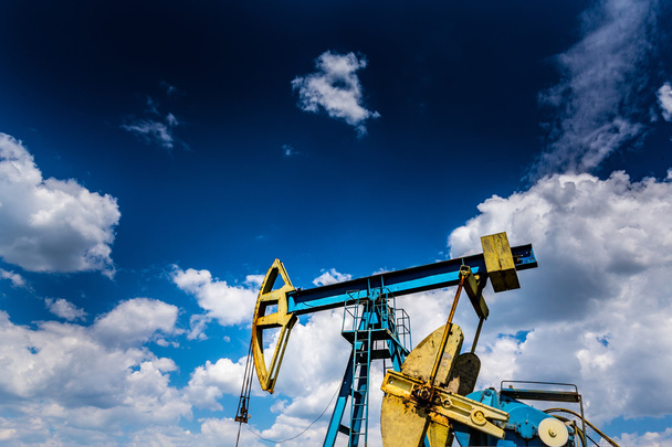 Operating oil well profiled on dramatic cloudy sky - Photo, Image