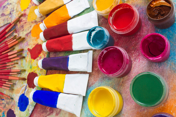 Paints, brushes and palette on the colorful background. - Valokuva, kuva