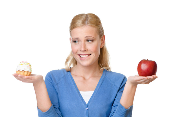 Beautiful woman makes a choice between cake and apple - Photo, image