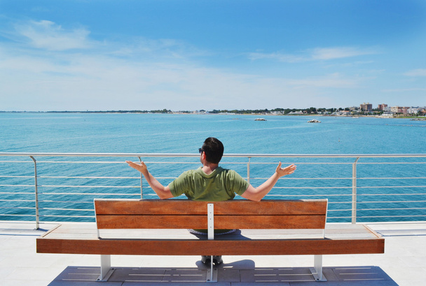 Man zittend op een bankje aan de zee - Foto, afbeelding