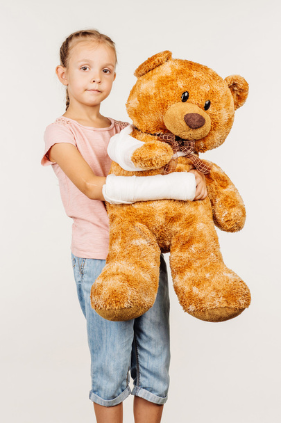Young girl with broken arm in shirt and blue jeans is standing - Foto, immagini