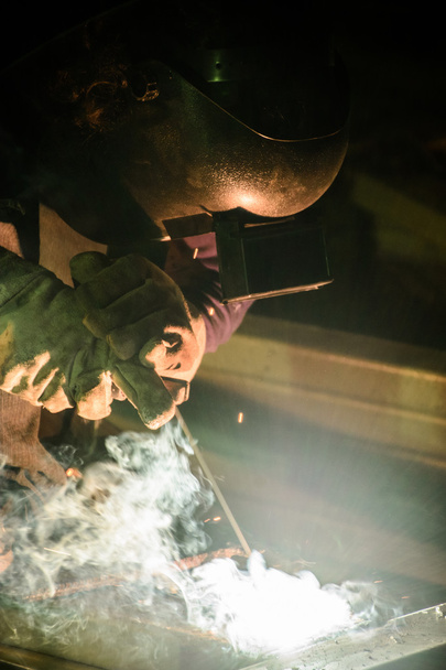 A fémmunkások kézi munkát használnak, képzett hegesztőt, gyármunkásokat, akik túlóráznak. A hegesztő hegeszti az acélt a gyárban.. - Fotó, kép