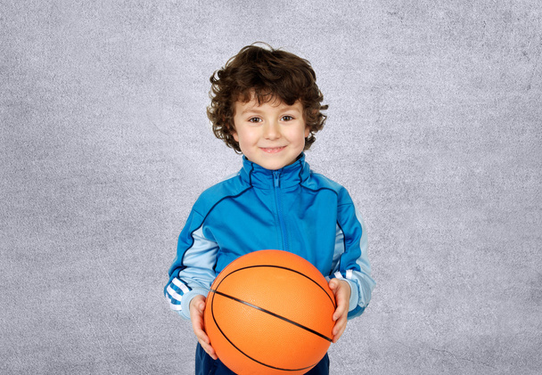 Улыбающийся мальчик смотрит в камеру с баскетбольным мячом
 - Фото, изображение