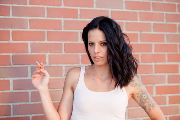 Femme brune rebelle avec chemise serrée fumant une cigarette
 - Photo, image