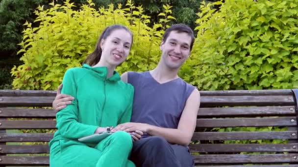 Beautiful Young Couple Sitting Resting on a Park Bench. They Hug Each Other and Kiss. - Footage, Video