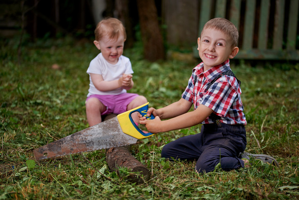 boy sawing fallen tree in garden - Zdjęcie, obraz