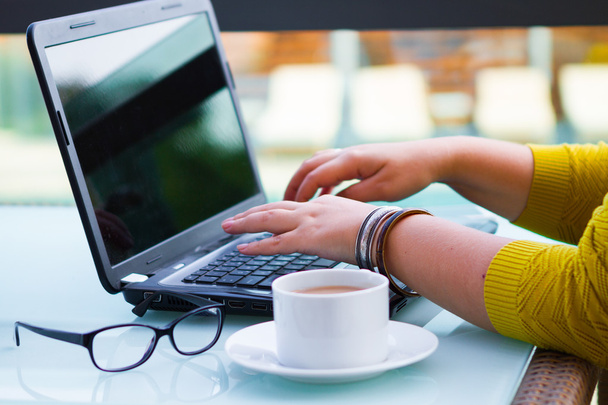 Mãos de mulher no teclado do seu computador portátil. Feminino trabalhando em laptop em um café de rua, tema de negócios
  - Foto, Imagem