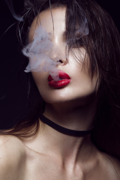 Beautiful sexy brunette girl with bright makeup, red lips, smoke from mouth. beauty face. - Fotografie, Obrázek