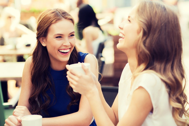 smiling young women with coffee cups at cafe - Photo, image
