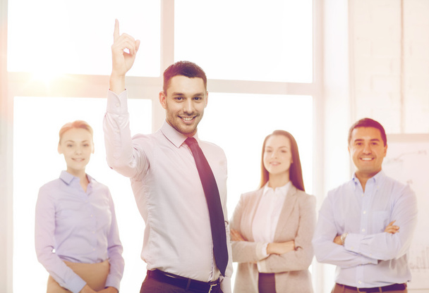 smiling businessman in office with team on back - Foto, imagen
