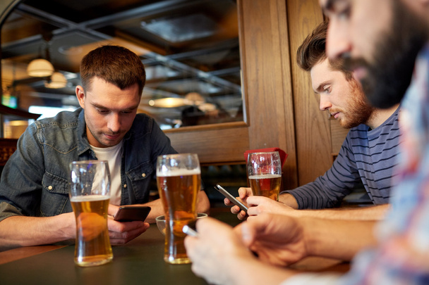 men with smartphones drinking beer at bar or pub - Foto, afbeelding