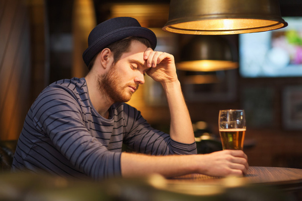 unhappy lonely man drinking beer at bar or pub - 写真・画像
