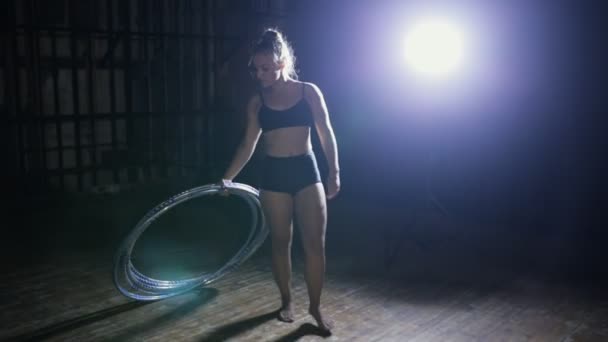 Acrobatic woman performer rotate hula hoop on dark scene - Felvétel, videó