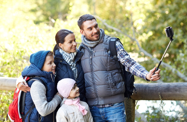 happy family with smartphone selfie stick in woods - Foto, Imagen