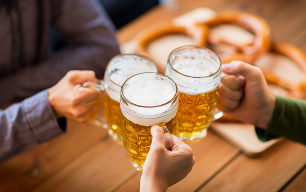 close up of hands with beer mugs at bar or pub - Foto, afbeelding