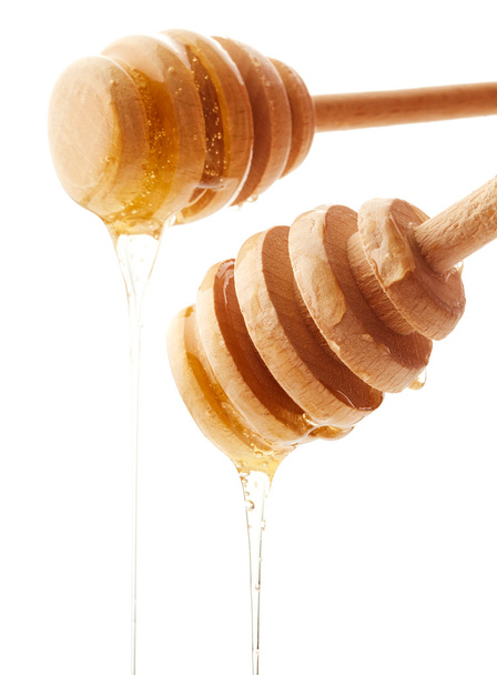 Honey dripping from wooden honey dippers  - 写真・画像
