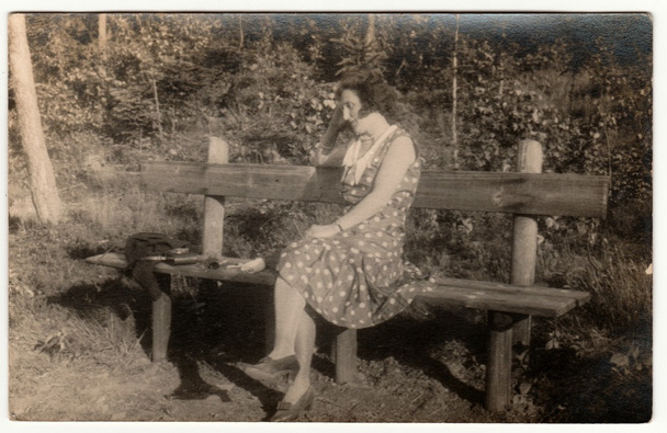 Vintage photo shows woman sits on the wooden bench in the park. Retro black & white photography. - Photo, Image