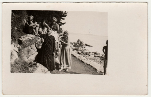 Jahrgangsfoto zeigt Menschen im Urlaub (Urlaub). Sie stehen am Ufer des Meeres. Retro Schwarz-Weiß-Fotografie. - Foto, Bild
