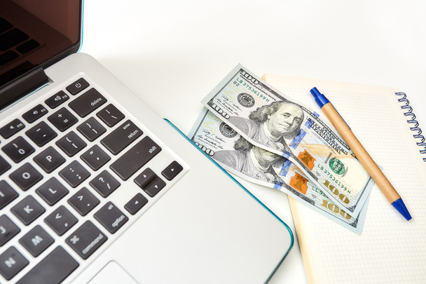 Close-up of laptop and money on a notepad - Foto, Imagen