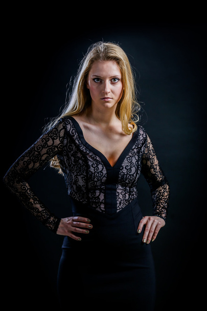 blonde girl on a black background in a dark guipure dress - Fotografie, Obrázek