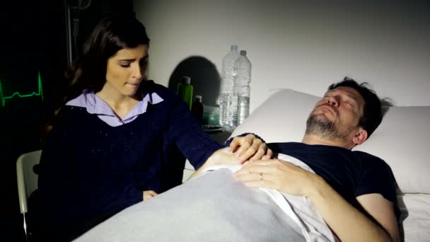 Treurige vrouw in ziekenhuis met hand van zieke vriend - Video
