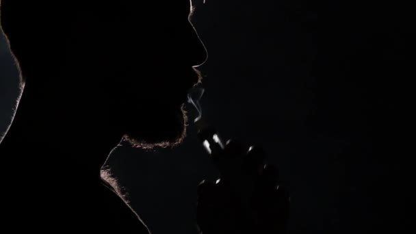 Ο άνθρωπος ηλεκτρονικό τσιγάρο κάπνισμα σε μαύρο. Σιλουέτα. Κοντινό πλάνο - Πλάνα, βίντεο