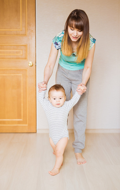 Мама учит своего милого маленького сына ходить, держа за руки часть тела первого ребенка шаги концепции
 - Фото, изображение