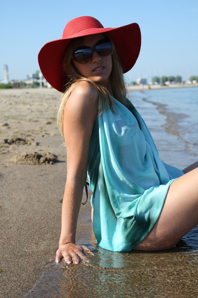 Happy young woman in swimsuit, sunglasses and red hat - Photo, Image