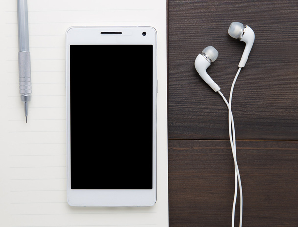 Bílý smartphone se sluchátky na staré dřevěné desce - Fotografie, Obrázek