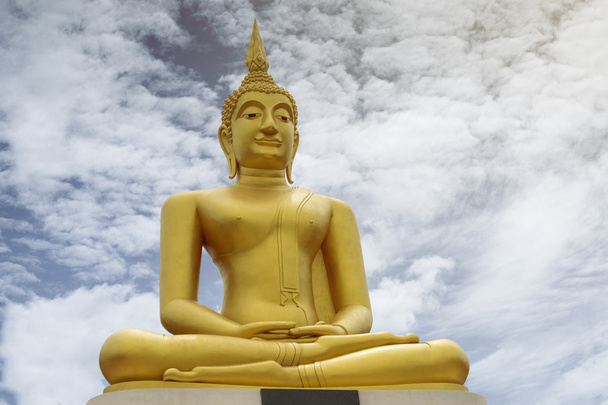 Gold image of Buddha with blue sky and cloud in background,  light effect added , prachuapkhirikhan,thailand,filtered image - Photo, Image