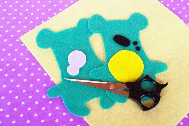 Домашний набор из зеленых животных, ножницы на фиолетовом фоне с горошек. Швейный проект для детей. Следы медведей вырезаны из войлока. Как сделать мягкую игрушку дома. Шаг за шагом
 - Фото, изображение